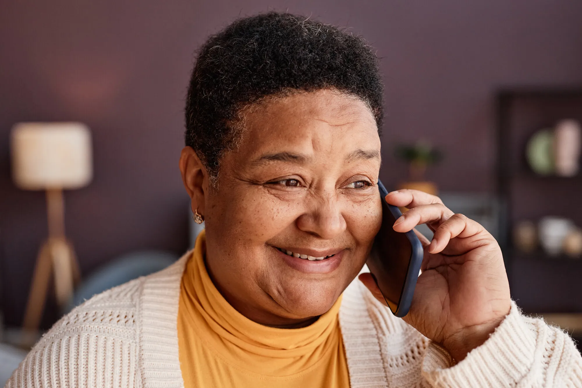A New Orleans neighbor smiling on a phone call at home